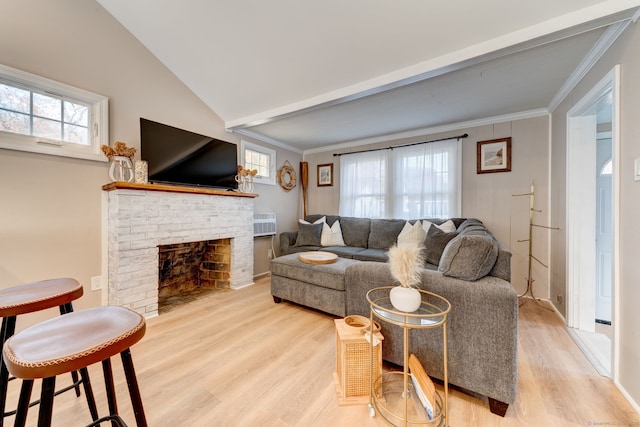 living area with lofted ceiling with beams, light wood-style floors, a fireplace, and crown molding