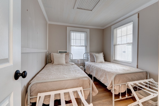 bedroom with multiple windows, crown molding, and wood finished floors