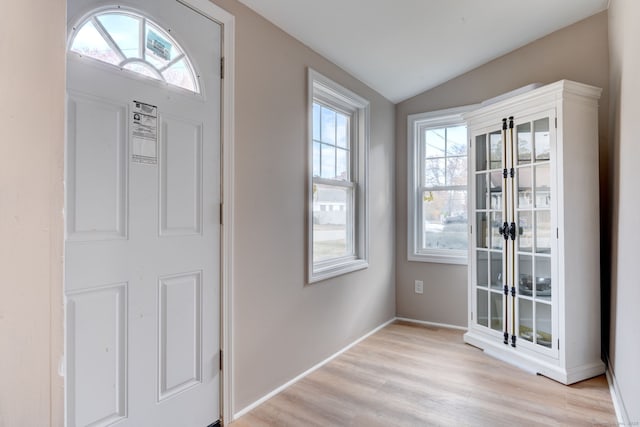 foyer featuring light wood-type flooring, vaulted ceiling, and baseboards