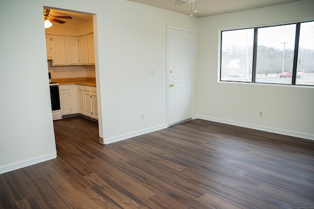 interior space featuring a ceiling fan, baseboards, and dark wood-style floors