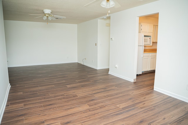 unfurnished room with a textured ceiling, baseboards, dark wood-type flooring, and a ceiling fan