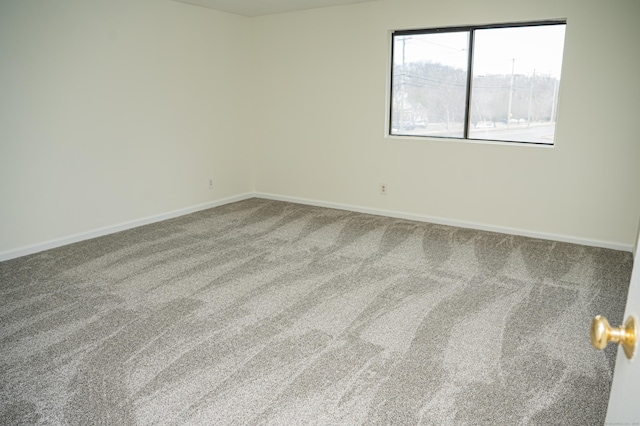 spare room featuring carpet floors and baseboards