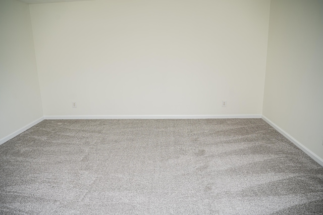 unfurnished room with carpet and baseboards