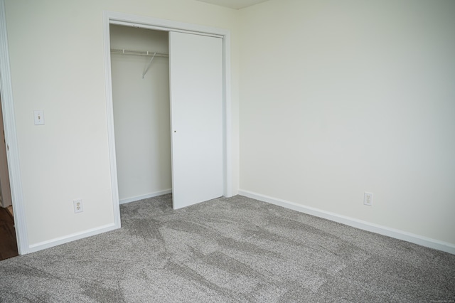 unfurnished bedroom with carpet, a closet, and baseboards