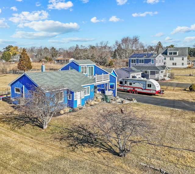 view of front facade with driveway, a front yard, and roof with shingles