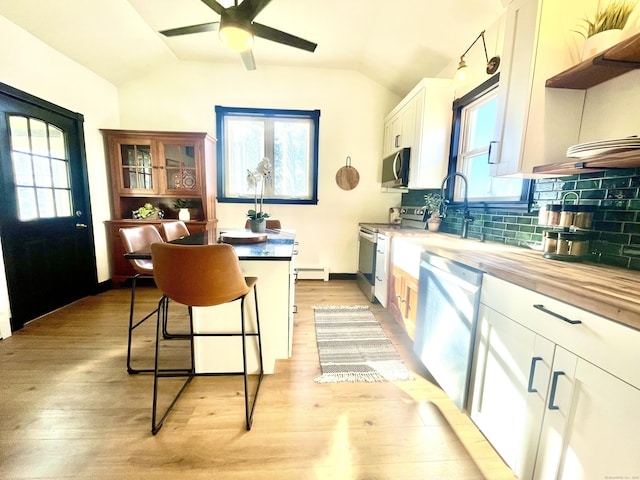 kitchen featuring light wood-type flooring, a baseboard radiator, lofted ceiling, and appliances with stainless steel finishes