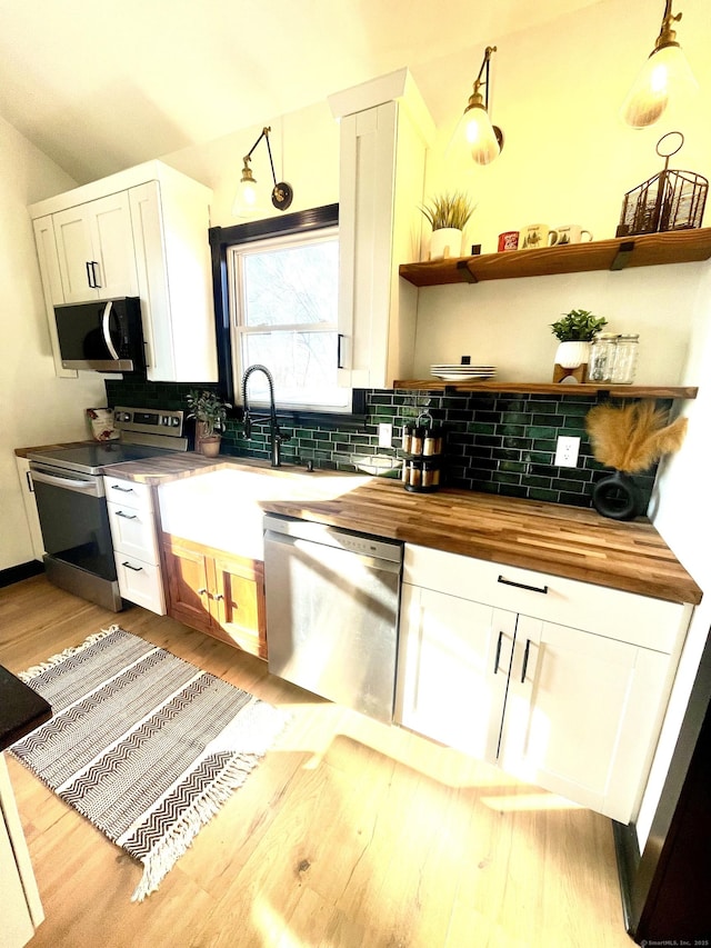 kitchen featuring butcher block countertops, tasteful backsplash, appliances with stainless steel finishes, and white cabinets