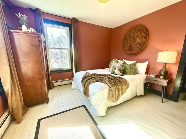 bedroom with baseboard heating and wood-type flooring