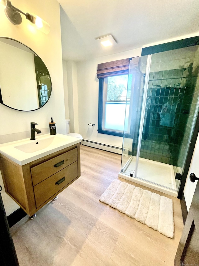 bathroom with vanity, wood finished floors, a stall shower, toilet, and baseboard heating