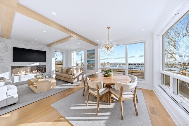 sunroom / solarium featuring a chandelier, beam ceiling, visible vents, and a fireplace