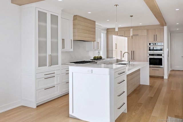 kitchen featuring double oven, gas cooktop, light wood-style flooring, and a sink