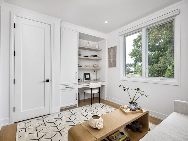 office featuring light wood-style floors, built in desk, and baseboards