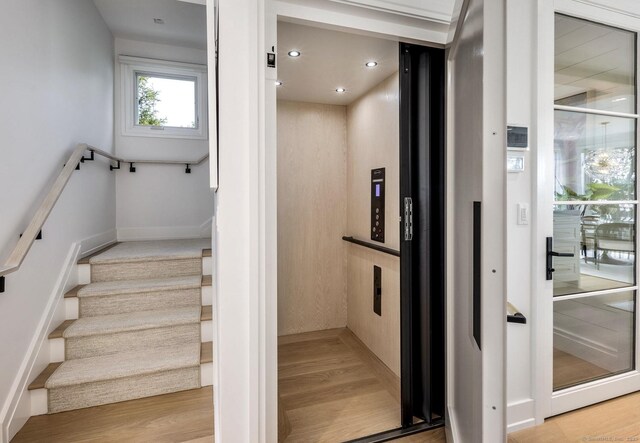 stairway with recessed lighting, elevator, baseboards, and wood finished floors