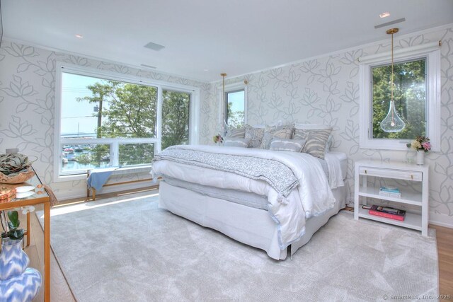 bedroom featuring wood finished floors, multiple windows, baseboards, and wallpapered walls