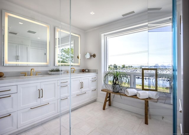 bathroom with double vanity, crown molding, visible vents, and a sink