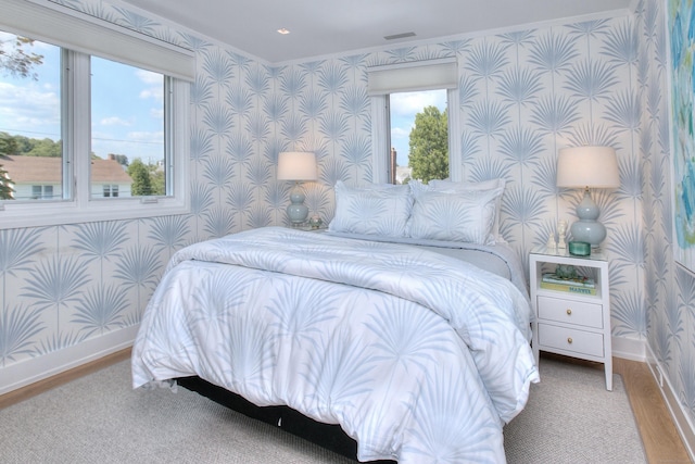 bedroom with baseboards, wood finished floors, and wallpapered walls