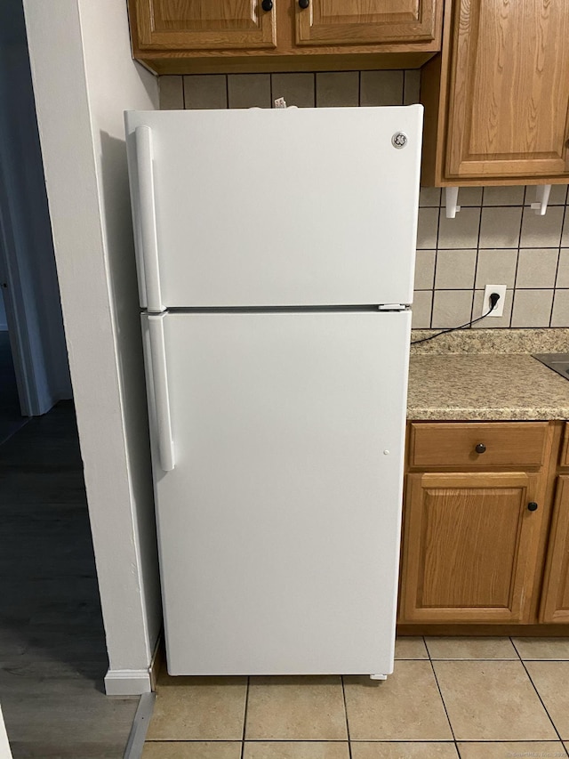 kitchen with light tile patterned floors, freestanding refrigerator, and decorative backsplash