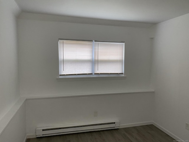 empty room featuring a baseboard radiator, baseboards, and wood finished floors