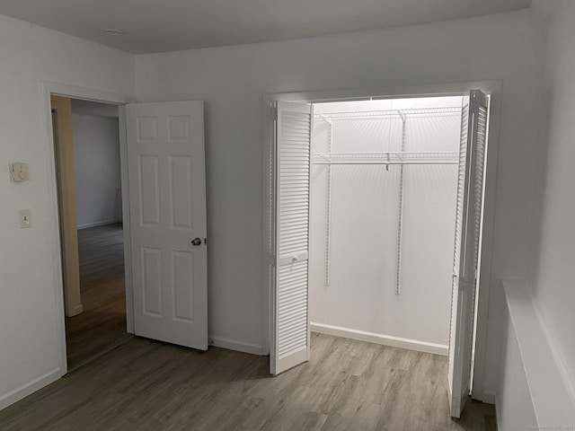 unfurnished bedroom featuring baseboards, a closet, and light wood-style floors