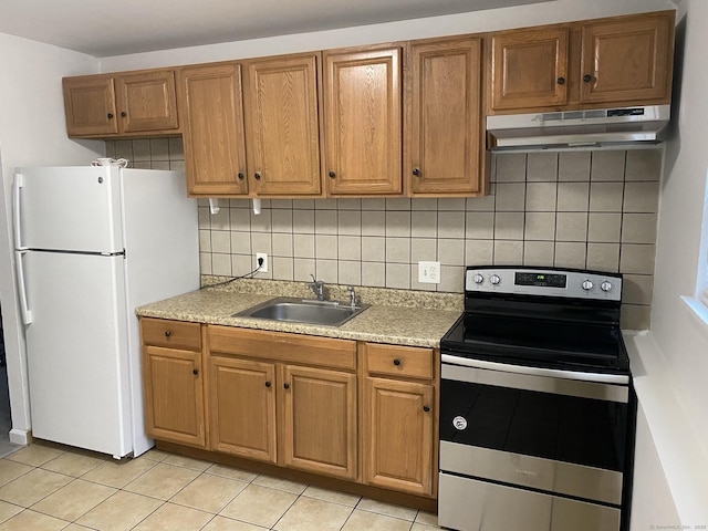 kitchen featuring electric stove, light countertops, freestanding refrigerator, a sink, and under cabinet range hood