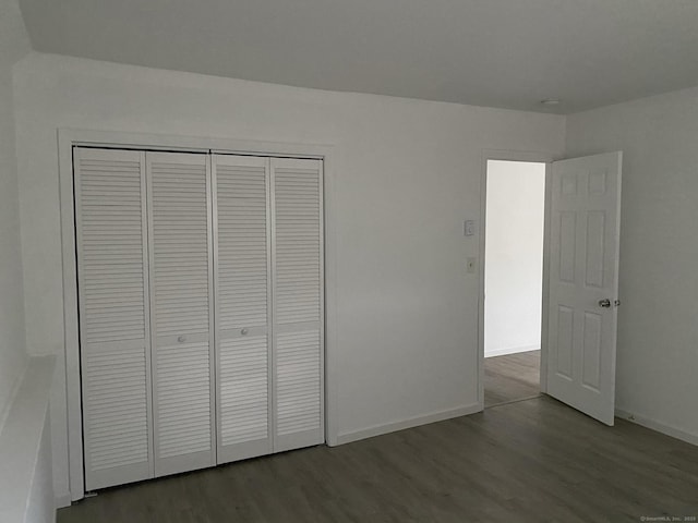 unfurnished bedroom with a closet, wood finished floors, and baseboards