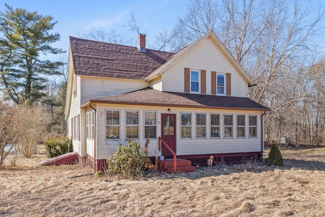 exterior space with entry steps, a shingled roof, and a chimney