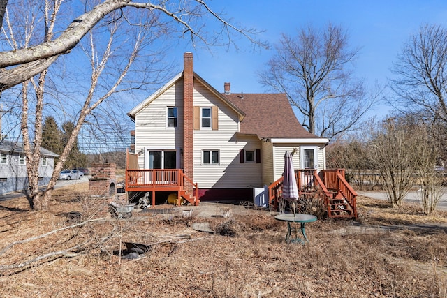 rear view of property with a shingled roof, a chimney, and a wooden deck