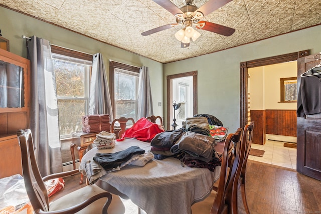 dining area featuring ceiling fan, a baseboard radiator, a baseboard heating unit, wainscoting, and an ornate ceiling