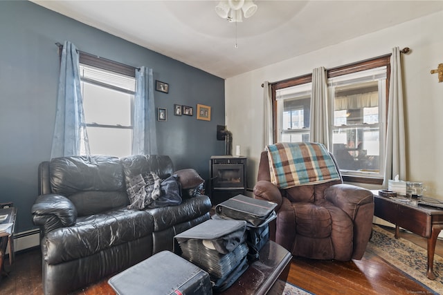 living area with a ceiling fan, a baseboard radiator, dark wood-style flooring, and a wood stove