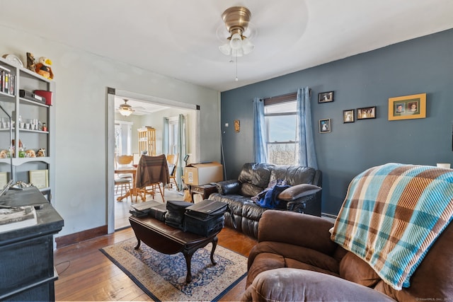 living area featuring a baseboard heating unit, baseboards, a ceiling fan, and hardwood / wood-style floors