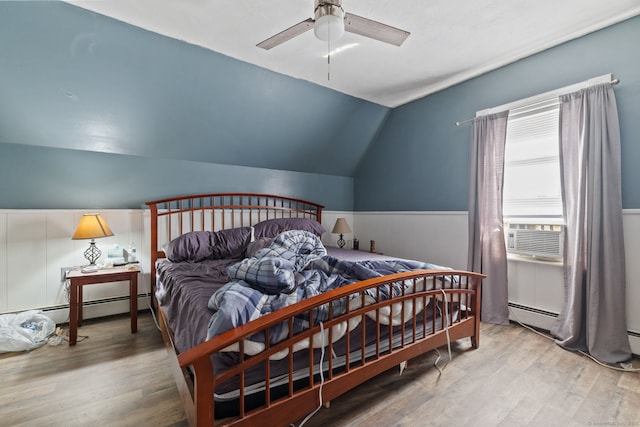 bedroom featuring lofted ceiling, a wainscoted wall, a baseboard radiator, wood finished floors, and cooling unit