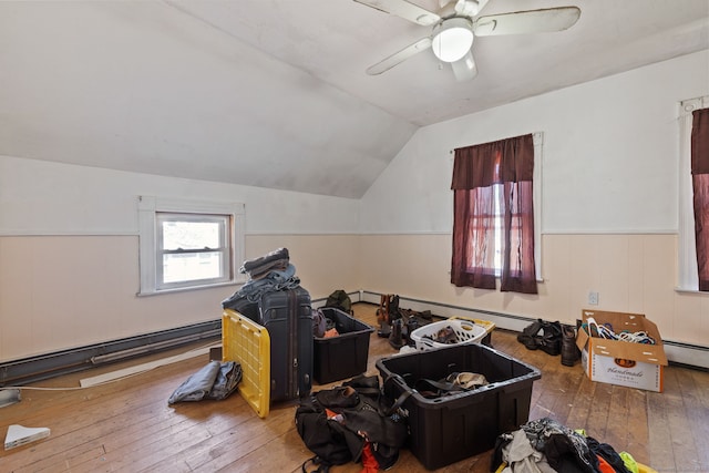 bonus room with a wainscoted wall, baseboard heating, vaulted ceiling, ceiling fan, and hardwood / wood-style floors