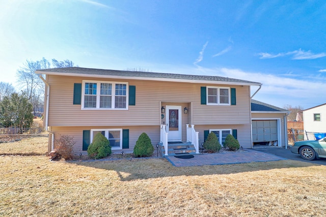 split foyer home with a garage, a front yard, and fence