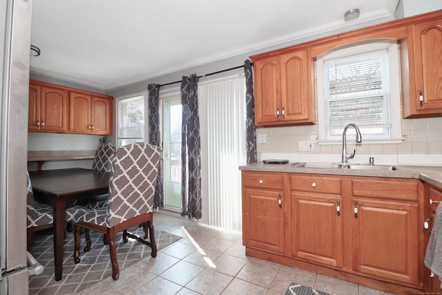 kitchen with ornamental molding, a sink, brown cabinetry, light countertops, and decorative backsplash