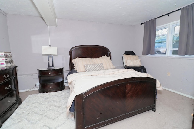 bedroom featuring baseboards, beam ceiling, and carpet