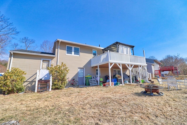 back of property with stairs, a wooden deck, a yard, and an outdoor fire pit