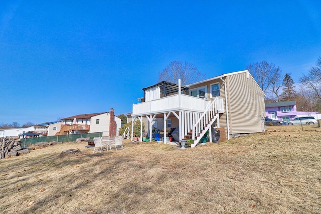 rear view of house featuring stairway, a lawn, fence, and a wooden deck