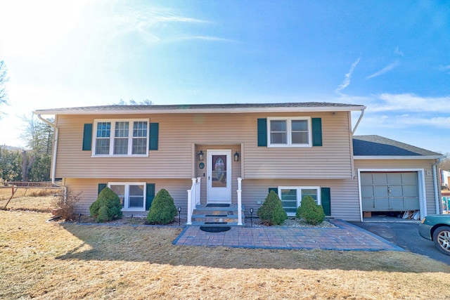 split foyer home featuring driveway, a front yard, an attached garage, and entry steps