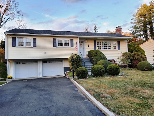 view of front of property featuring aphalt driveway, a garage, a front lawn, and a chimney