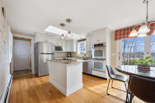 kitchen with light stone counters, stainless steel appliances, light wood-style floors, a baseboard heating unit, and a notable chandelier