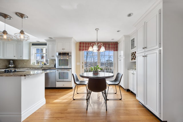 kitchen featuring dark stone counters, white cabinets, appliances with stainless steel finishes, light wood-type flooring, and backsplash