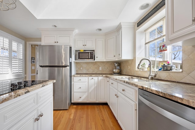 kitchen featuring light wood finished floors, backsplash, stainless steel appliances, and a sink