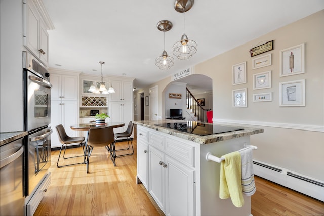 kitchen with arched walkways, white cabinets, appliances with stainless steel finishes, baseboard heating, and a center island