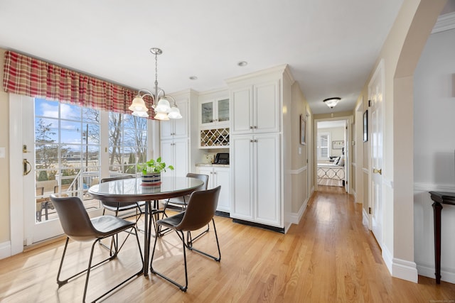 dining space with a notable chandelier, light wood-type flooring, and baseboards