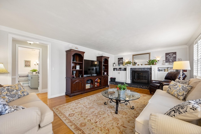 living room featuring light wood-type flooring, baseboards, a premium fireplace, and crown molding