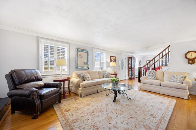 living area featuring ornamental molding, stairway, light wood-style floors, a baseboard radiator, and baseboards