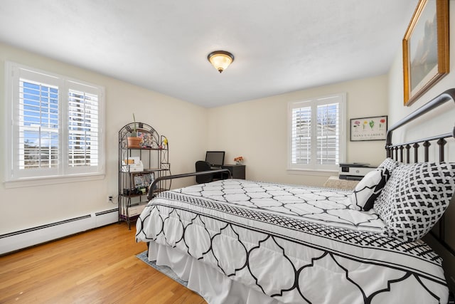 bedroom featuring light wood-type flooring and a baseboard heating unit