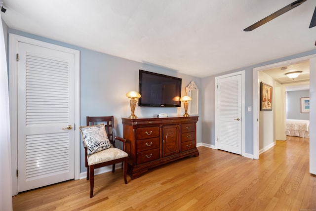 living area featuring baseboards, light wood finished floors, and ceiling fan