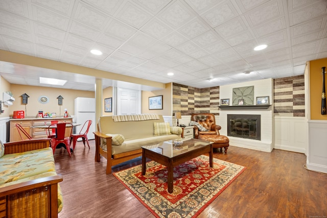 living room featuring recessed lighting, wainscoting, a brick fireplace, and wood finished floors