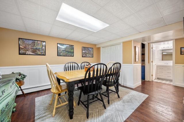 dining area featuring wainscoting, dark wood-type flooring, and a baseboard radiator